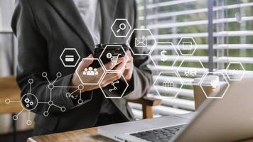 Hands of woman using mobile phone in modern office with laptop and digital tablet computer with VR icon diagram at office photo