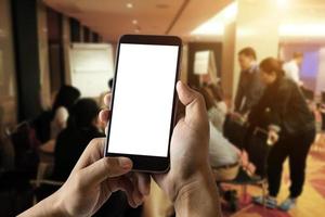 A man hand holding smart phone device in meeting room photo