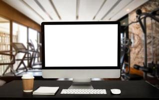 Computer Monitor, Keyboard, coffee cup and Mouse with Blank or White Screen Isolated is on the work table at the fitness gym photo