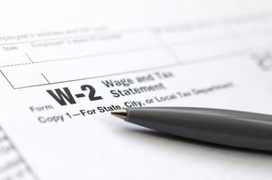 The pen lies on the tax form W-2 Wage and Tax Statement. The time to pay taxes photo