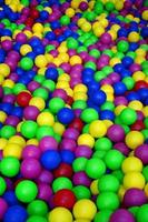 Many colorful plastic balls in a kids' ballpit at a playground. Close up pattern photo