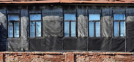 vieja pared de ladrillo desgastada con ventanas foto