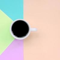 Small white coffee cup on texture background of fashion pastel pink, blue, coral and lime colors paper photo