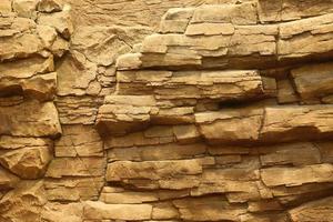 Light coarse natural rock stone background. Mining cliff rough front surface. Big limestone stack backdrop. Heavy grunge damaged granite block texture photo