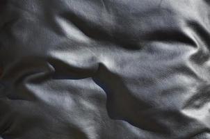 textura de cuero negro o dermantina con pliegues, utilizada como material para bolsos de mujer y hombre, maletas, almohadas para sofás de oficina y también para muebles tapizados foto