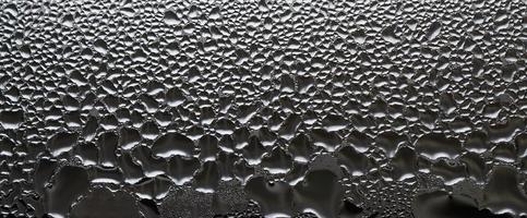 A photo of the glass surface of the window, covered with a multitude of droplets of various sizes. Background texture of a dense layer of condensate on glass