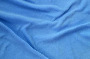 The blanket of furry blue fleece fabric. A background of light blue soft plush fleece material with a lot of relief folds photo