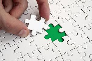 The human hand fills the last missing elements of the surface from the jigsaw puzzle. The concept of the completion of the initiated cases photo