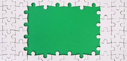 Framing in the form of a rectangle, made of a white jigsaw puzzle around the green space photo