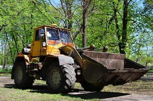 el equipo de mejora de la ciudad quita las hojas caídas en el parque con una excavadora y un camión. trabajo estacional regular en la mejora de los lugares públicos para la recreación foto