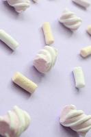 Colorful marshmallow laid out on violet paper background. pastel creative textured pattern. Perspective macro shot photo