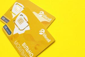 TERNOPIL, UKRAINE - JULY 5, 2022 Lifecell new sim card with free contract on yellow background. Lifecell is ukrainian mobile telephone network operator and provider of wireless connection photo