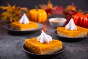 Rebanada de pastel de calabaza casero americano tradicional recién horneado que adorna la crema batida para celebrar las fiestas foto