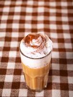 Pumpkin spice whipped latte in glass. Hot autumn drink beverage on checkered tablecloth photo