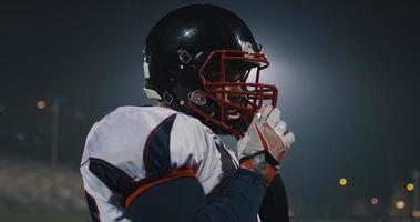 American Football Player Putting On Helmet on large stadium with lights in background photo