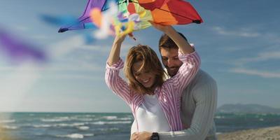 Happy couple having fun with kite on beach photo