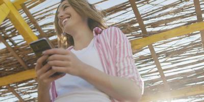 mujer smartphone enviando mensajes de texto por teléfono celular en la playa foto