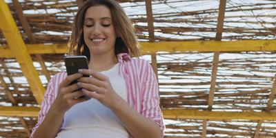 mujer smartphone enviando mensajes de texto por teléfono celular en la playa foto