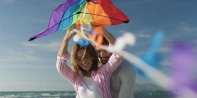 Happy couple having fun with kite on beach photo