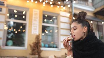 Woman in an outdoor cafe eats an iced pastry video