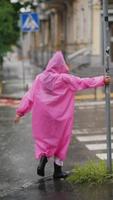 femme en poncho à capuchon rose navigue dans une rue de la ville sous la pluie video