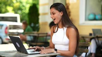 Woman sits at outdoor cafe using laptop video