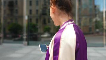 Woman stands on sidewalk texting on smartphone video