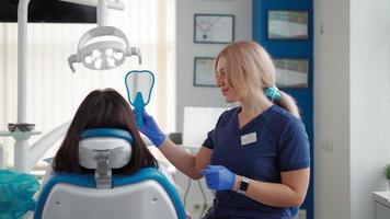 professionelle zahnärztin untersucht eine patientin mit einem speziellen werkzeug und verschreibt die behandlung in einer modernen zahnklinik. Mundhygiene. Konzept des Gesundheitswesens und der Medizin. Zeitlupe