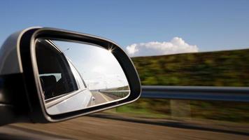 visie van van de kant spiegel de binnen van een het rijden auto langs de snelweg in een zonnig dag. concept van voertuigen en vervoer. Nee mensen. video