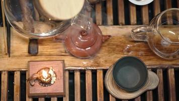 elaboración tradicional de té en una tabla para una ceremonia del té a la luz de las velas con una suave iluminación diurna. el hombre vierte agua hirviendo en una tetera. vista superior. persona irreconocible.