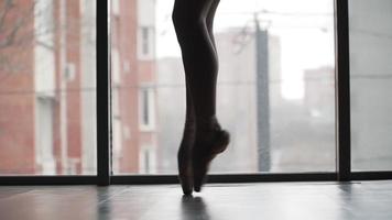Beautiful ballet feet Pointe shoes, the silhouette against the window and the city. Ballerina graceful gait. Slow motion. Close-up video