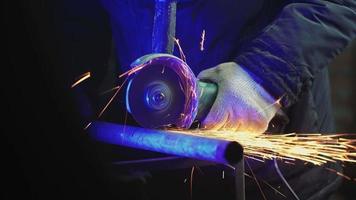 mecânico profissional corta tubos de metal com um moedor, prendendo-os em um torno. homem trabalha com serra circular. disco que gira e corta metal de perto. indústria siderúrgica e conceito de oficina.
