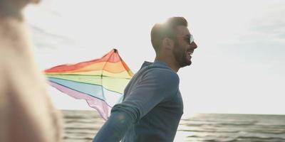 Happy couple having fun with kite on beach photo