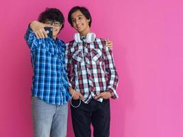 Photo of a young arab teenager taking a selfie photo with a smartphone isolated behind a purple wall. Selective focus