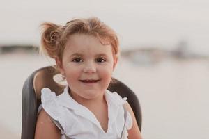 A portrait of a smiling little girl sitting in a bicycle seat. Selective focus photo