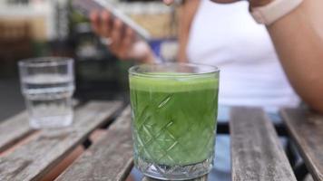 Woman taps ice cubes in green matcha tea latte video