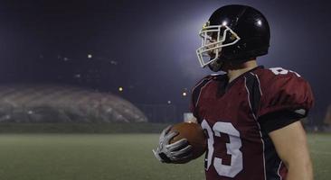 American football player holding ball while running on field photo