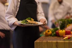 Chef hands holding dish of fried Salmon fish fillet photo