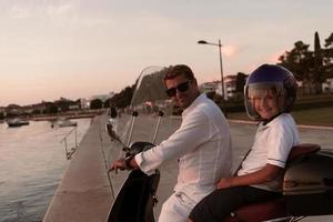 un padre con su hijo disfruta de unas vacaciones montando una moto junto al mar temprano en la mañana. enfoque selectivo foto