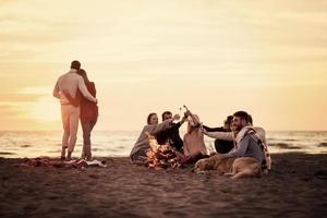 Couple enjoying with friends at sunset on the beach photo