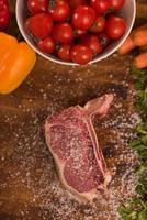 Juicy slice of raw steak on wooden table photo