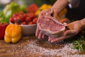 chef sosteniendo una jugosa rebanada de bistec crudo foto