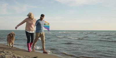 couple with dog having fun on beach on autmun day photo