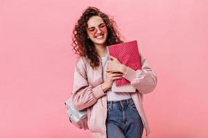 Optimistic woman in silk jacket and jeans holding notebooks photo