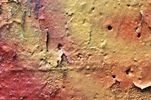 Detailed and colorful close up at cracked and peeling paint on concrete wall textures in high resolution photo