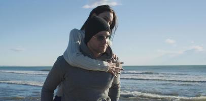 pareja divirtiéndose en la playa durante el otoño foto