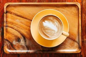 Top view of a latte art coffee on old wooden table. photo