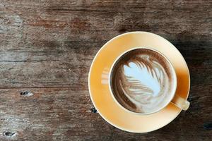 Top view of a latte art coffee on old wooden table. photo