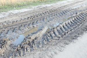 Autumn landscape with a curved road and traces of the tread of large wheels of agricultural machinery photo