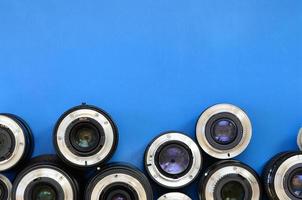 Several photographic lenses lie on a bright blue background. Space for text photo